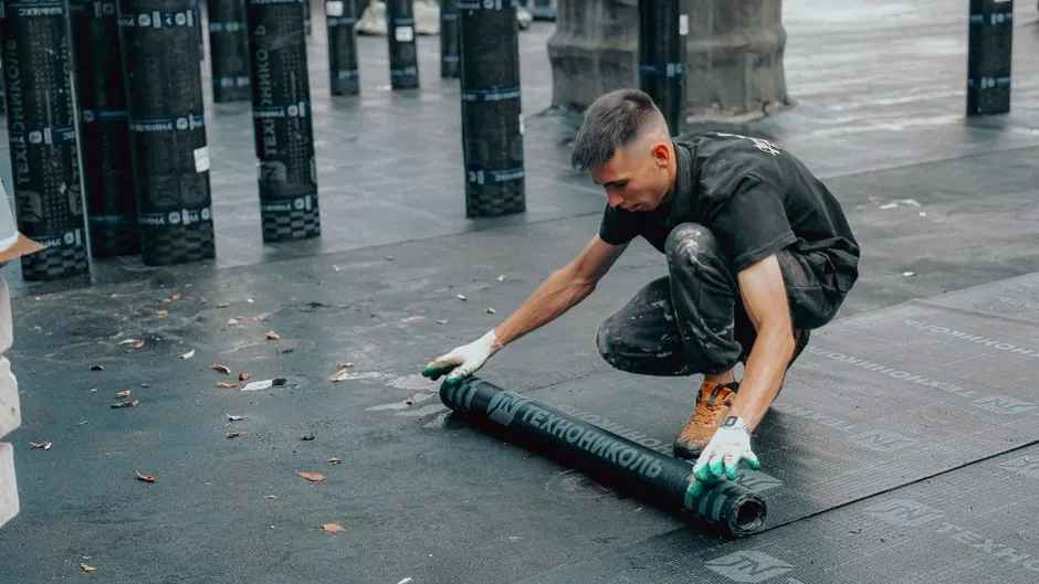 A single-ply membrane being rolled out across a flat roof