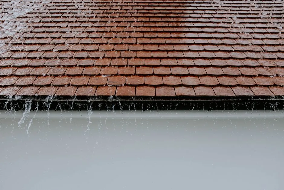 Rainwater running off the edge of a tiled roof instead of into the gutter